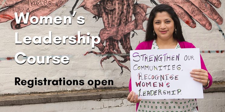 Woman holding a sign saying 'Strengthen our communities, recognise women's leadership'