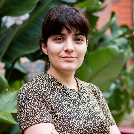 Picture of a woman with an animal print style shirt, and green leaves on the backgrounds