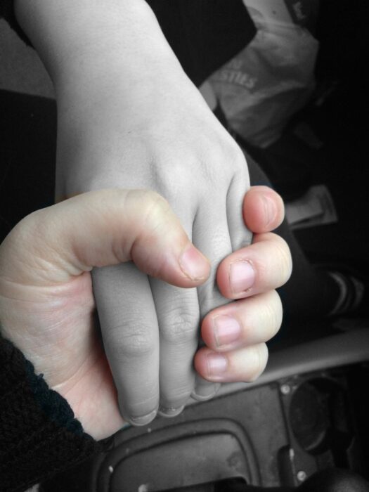 In this image, my son’s hand looks dead because when I was going through the court system I felt like I was being forced to let him go. The advocates were telling me that I had to let go. The cold hand represents how you feel walking through the system with your child. And knowing that any time my ex could decide he wants to have a crack at being a dad again, and I just have to let my son go. You are made to feel like you are making trouble and being uncooperative by not wanting them to see their kid, but it wasn’t like that. It was because I was scared. One hand clasps another smaller hand. In contrast to the first hand, the image is in black and white, so that the smaller hand is a pale grey.