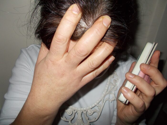 Speaking out against Family Violence/Abuse is like trying to get through to a mobile phone provider. Speaking out takes a sense of strength that is inconceivable, to listen takes an inconceivable sense of understanding. The ones who are brave to speak out are usually met with contempt. So is it any surprise that many suffer in silence. Who among us have not been affected by family violence/abuse? I wager not many. So perhaps we can take off our beautifully constructed masks and tell the truth and maybe then we might start Truly Listening. Very close to the camera a woman is holding her head in one hand and holding her mobile phone in the other. We cannot see her face.